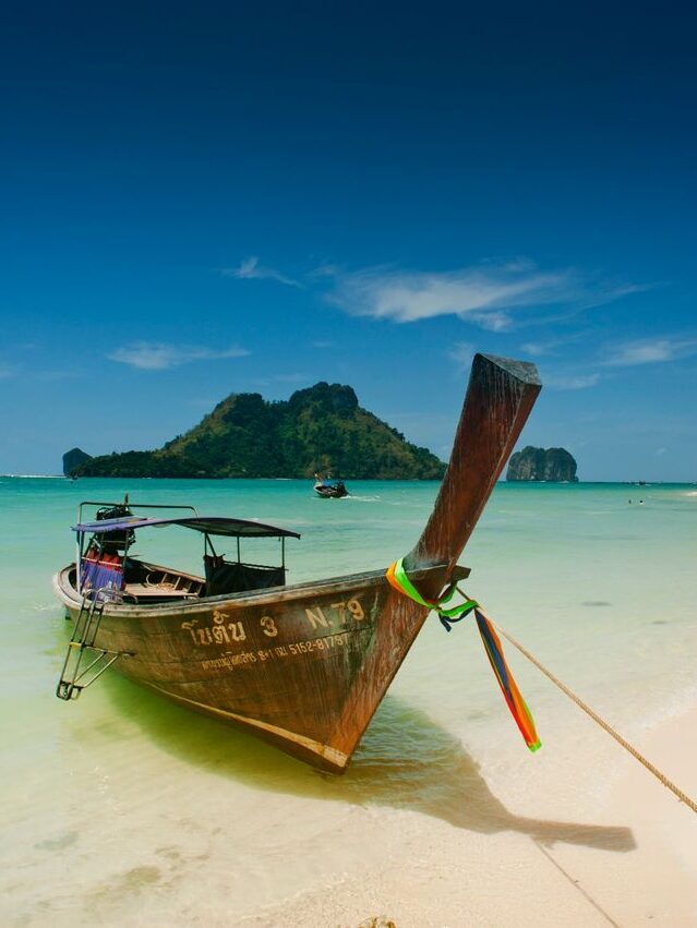 Scenic view of a traditional longtail boat on Ao Nang's turquoise beach in Krabi, Thailand.